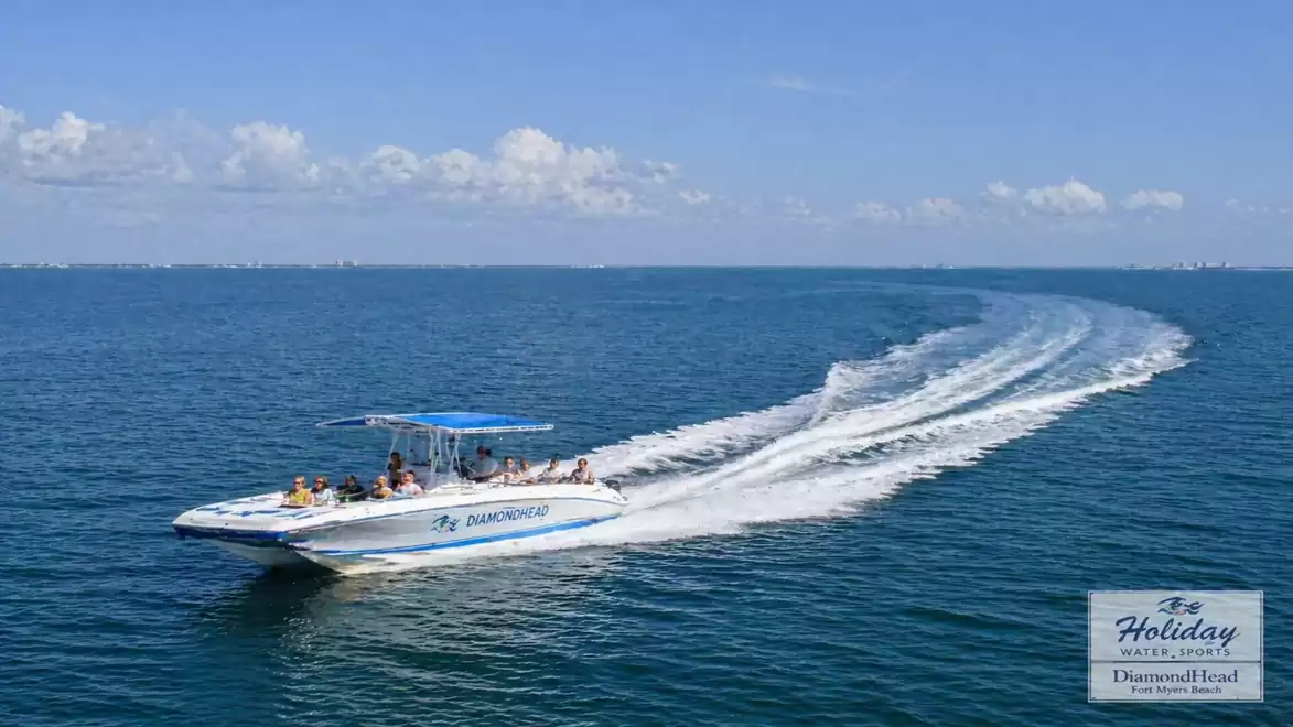 A speedboat with tourists travels over the blue sea under a clear sky.