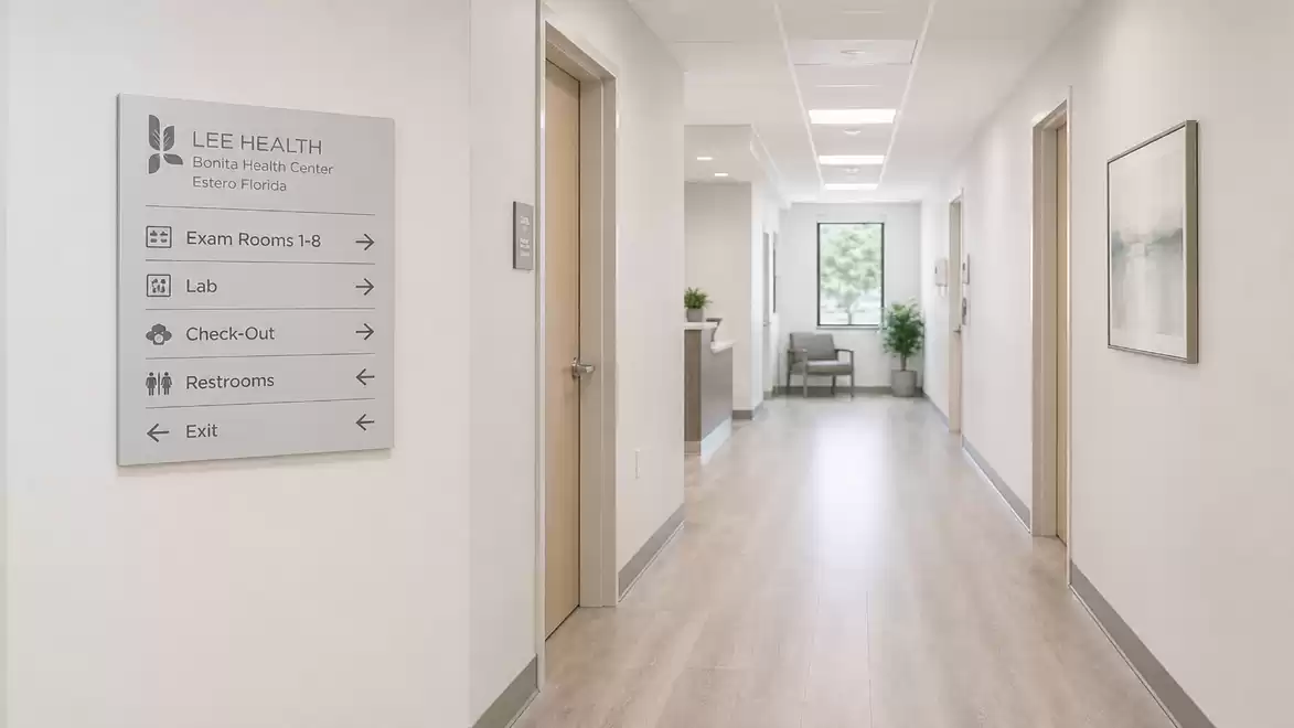 Modern doctor's office with a bright corridor view, left wall has signage to various rooms like labs, restrooms, and check-out.