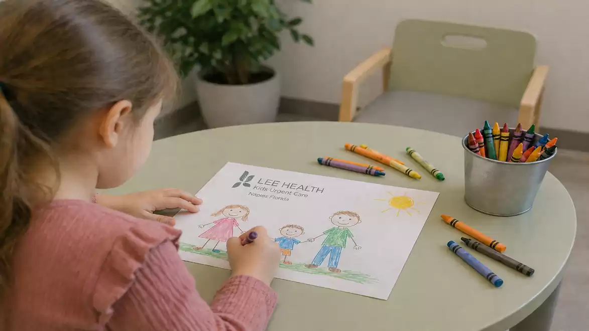 A girl is drawing a picture of a family with crayons at a table. Next to her, there is a bucket of multicolored crayons and a chair. A plant is visible in the background.