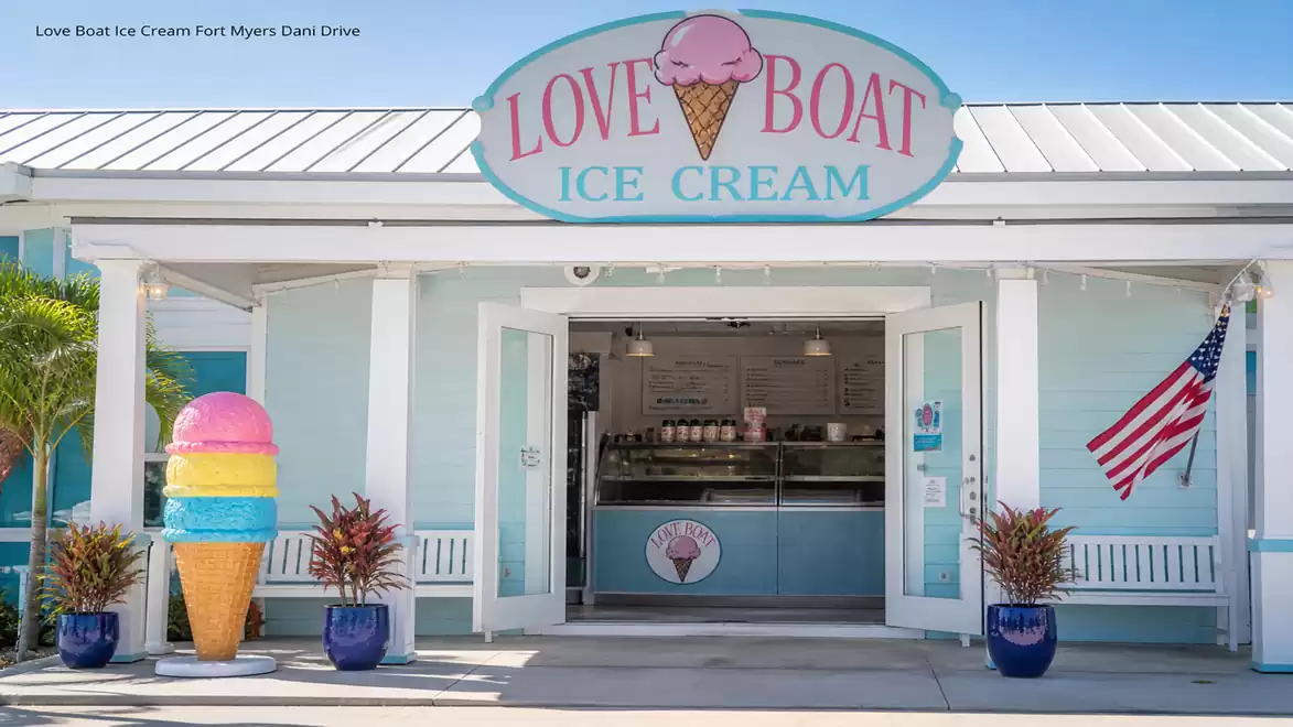 Entrance of an ice cream shop with large ice cream cone sculpture and American flag.