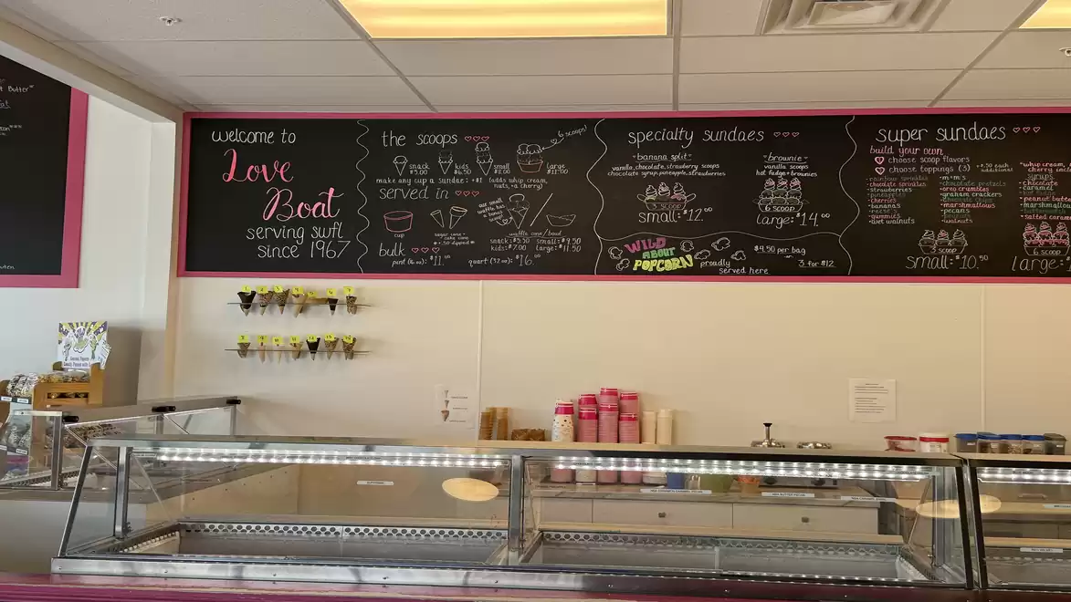 Image of an ice cream shop with a large chalkboard displaying the menu. The counter in the foreground is empty and the decor is inviting.