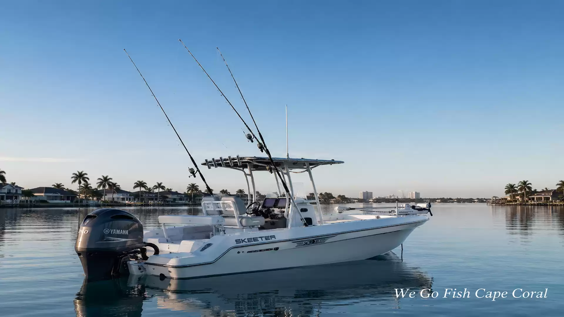 A white fishing boat with two fishing rods on a calm body of water at sunrise, surrounded by palm trees and a clear sky.