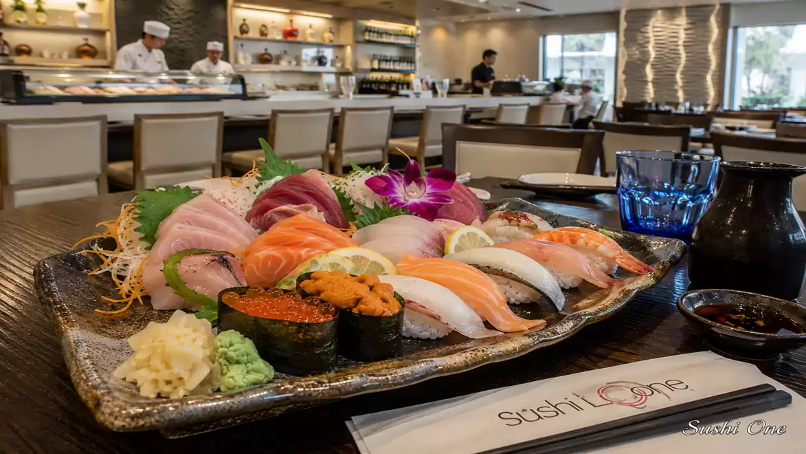 A plate of assorted sushi in a stylish Japanese restaurant with chefs in the background.