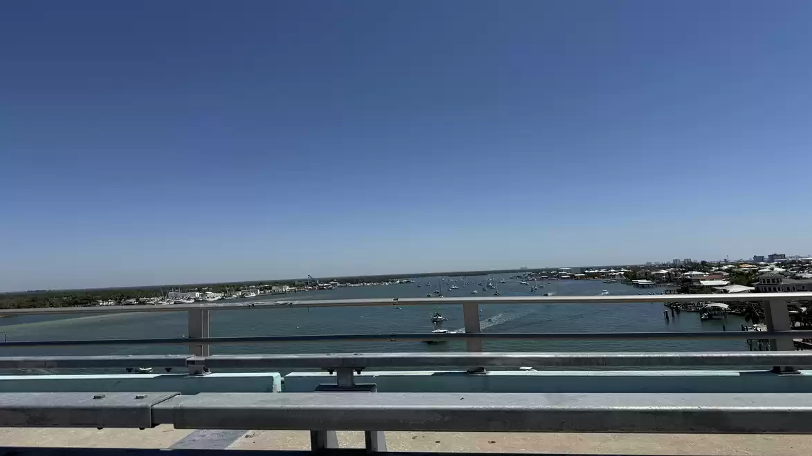 View from a bridge over a calm river under a clear blue sky.