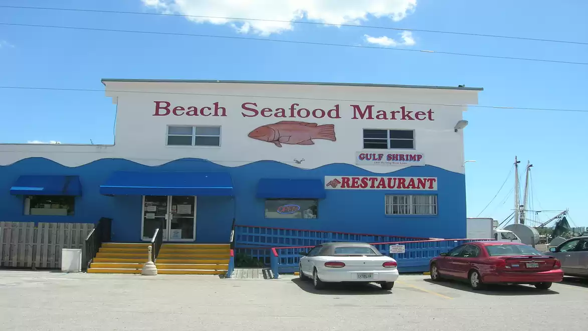 Blue and white building with restaurant and seafood market signage, two parked cars in front.