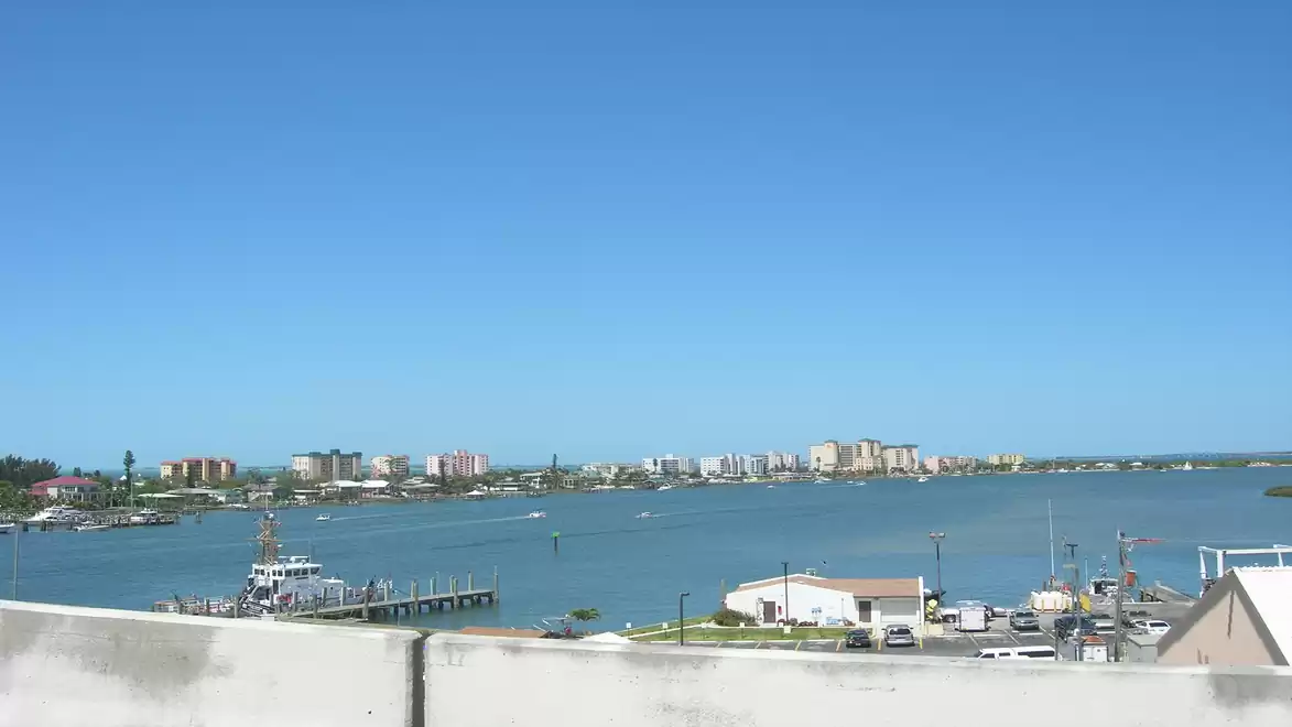 Coastal landscape with a boat dock, buildings, and blue sky.
