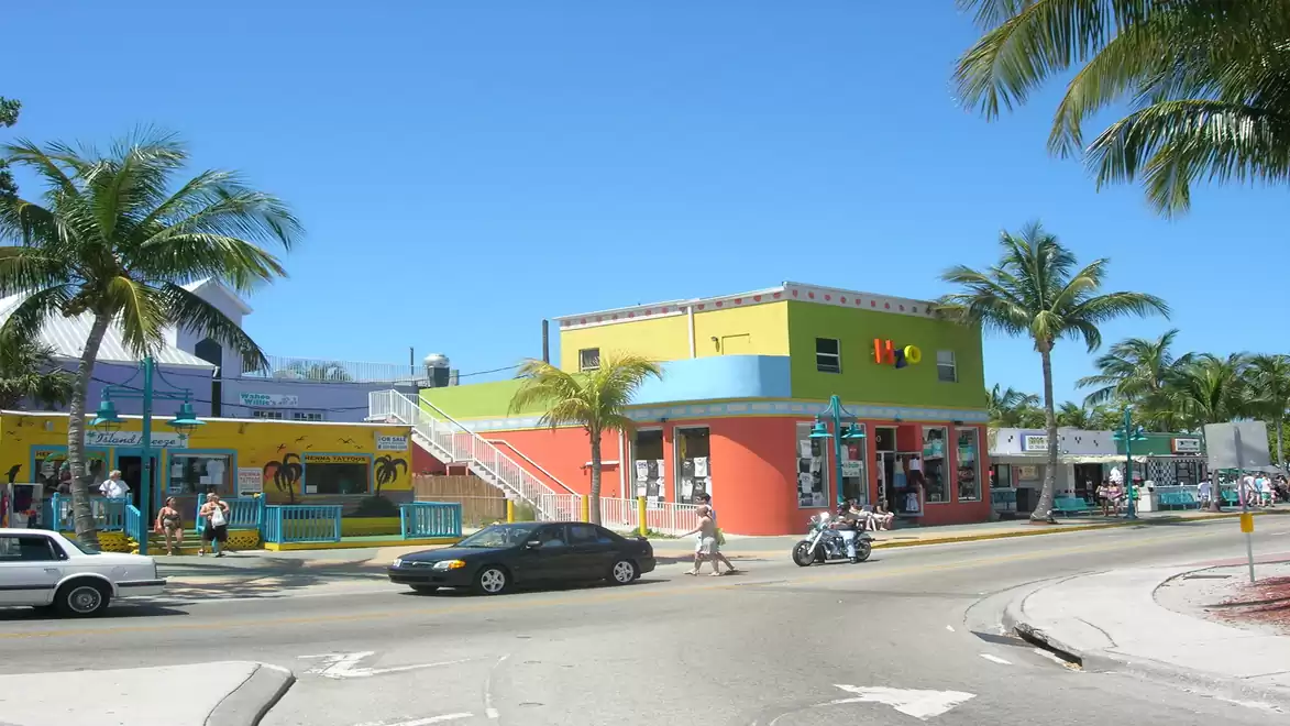 A vibrant street corner in Key West with colorful buildings and palm trees.