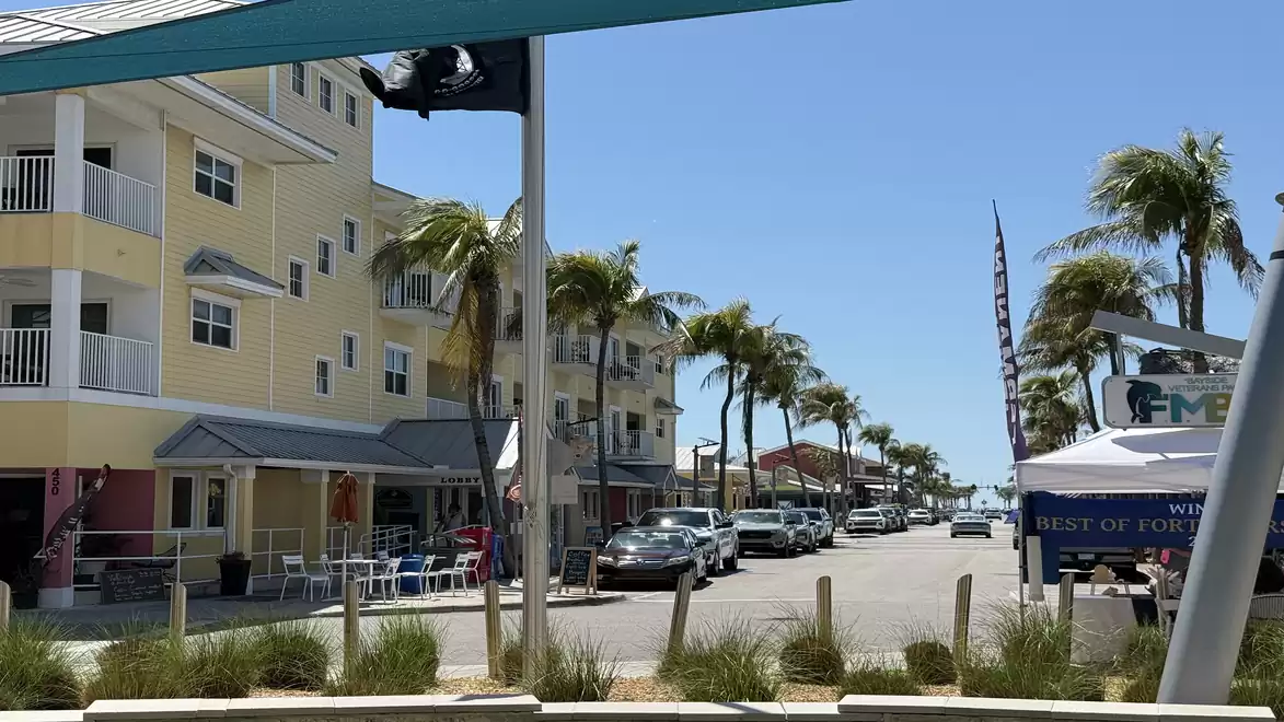 Street with palm trees and modern buildings on a sunny day.