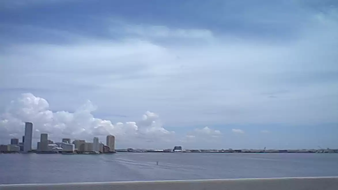 City skyline by the water under a blue sky with clouds