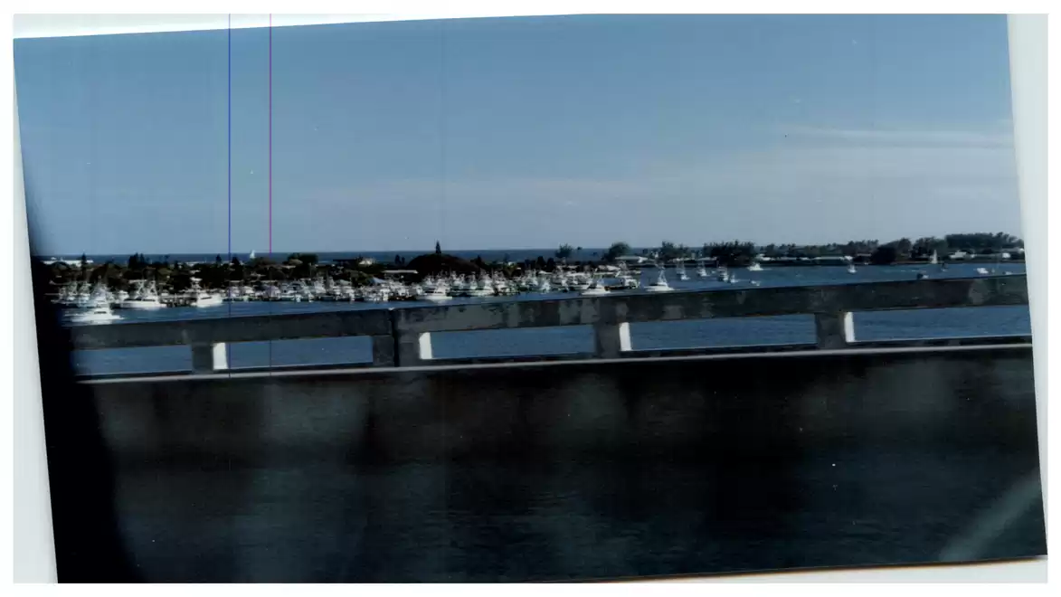 View of a coastal city and the ocean from a bridge, with a clear blue sky in the background.