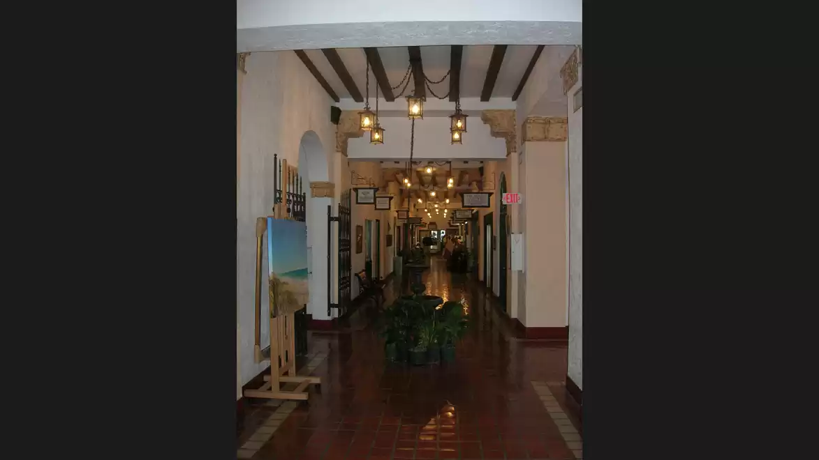 A long, artfully designed corridor with hanging lamps and displayed paintings.