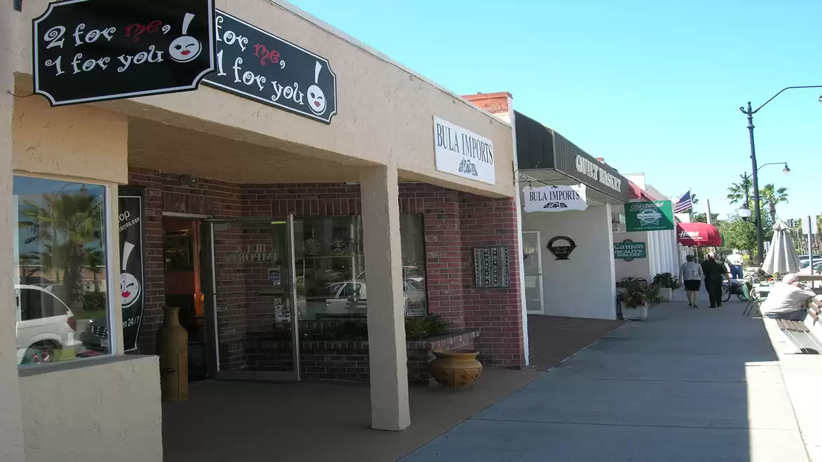 Street scene with shops and sidewalk in sunny weather.