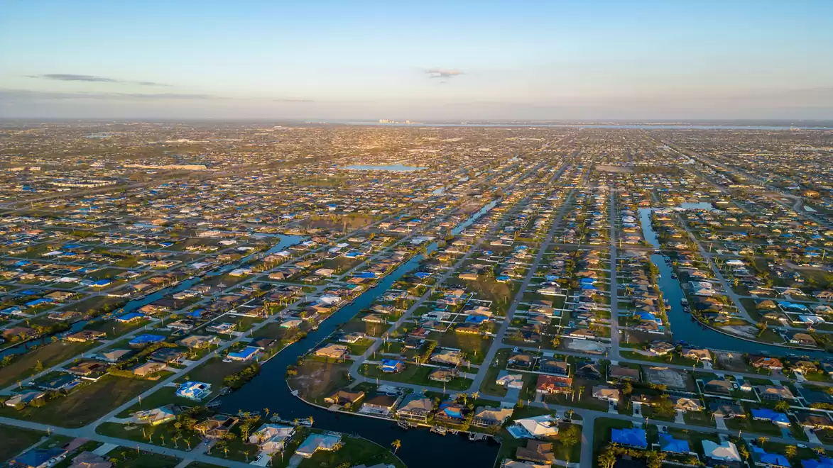 Aerial view of a vast residential area with many canals and houses under a blue sky at sunset.