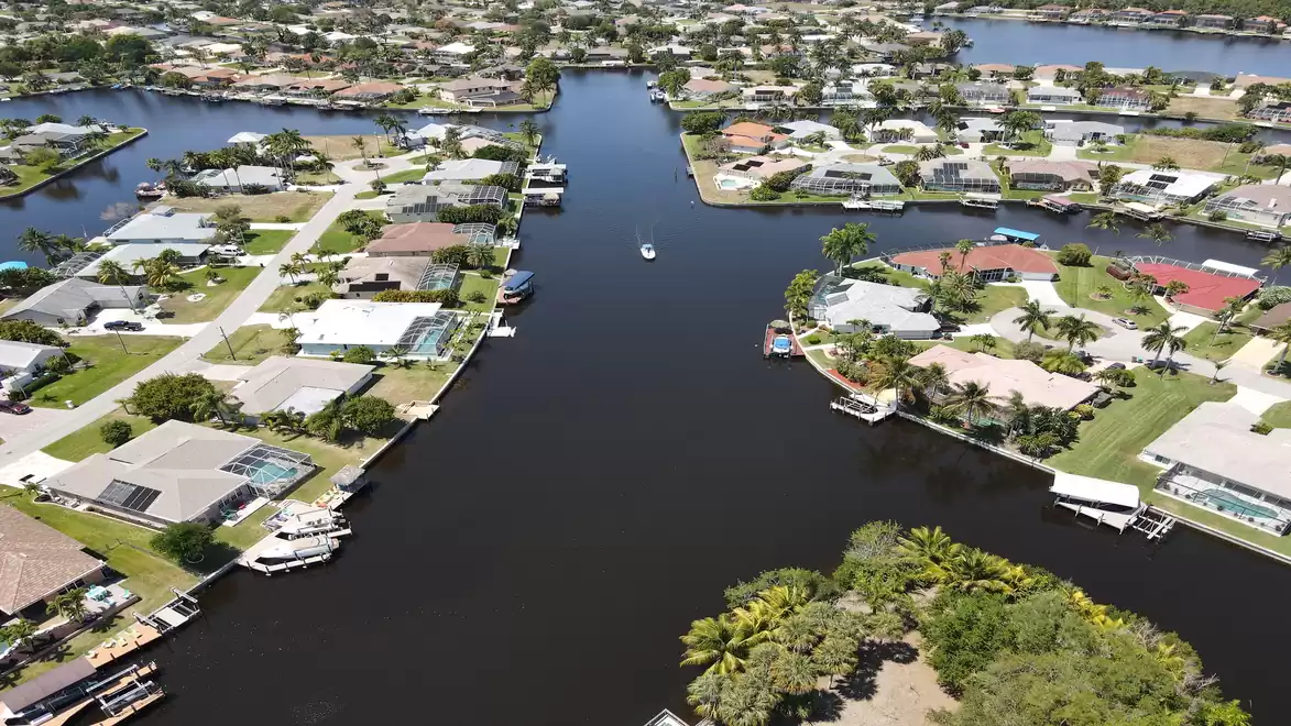 Aerial view of a residential area with waterways, surrounded by houses and green spaces.