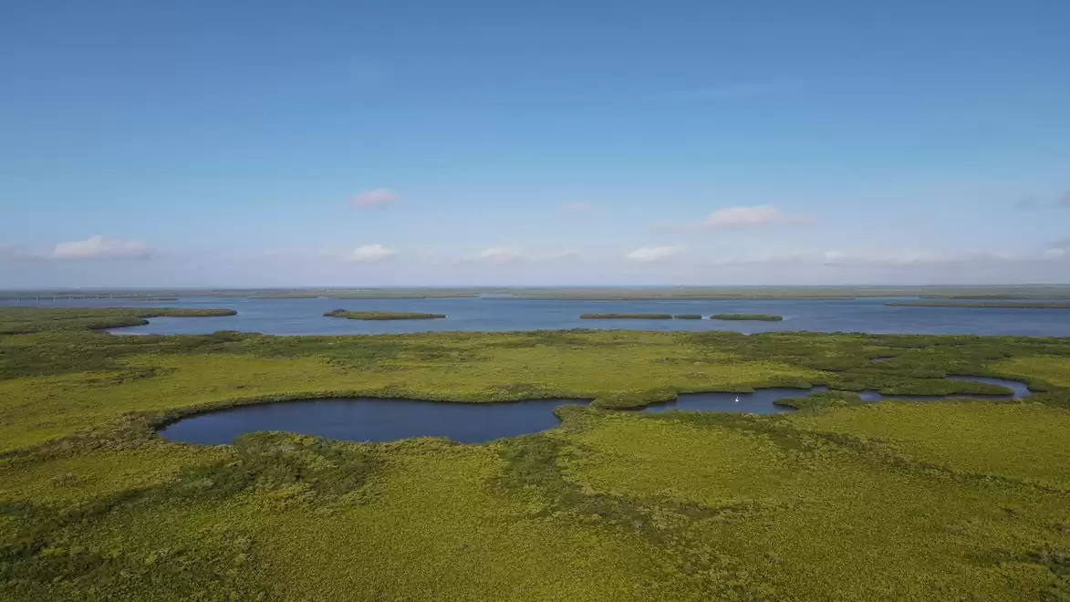 Landscape with green meadows and lakes under a blue sky.