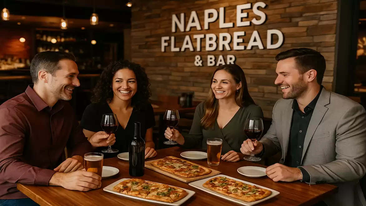 Four people laughing and eating flatbread in a restaurant, surrounded by glasses of red wine and beer. Background with 'NAPLES FLATBREAD & BAR' sign.