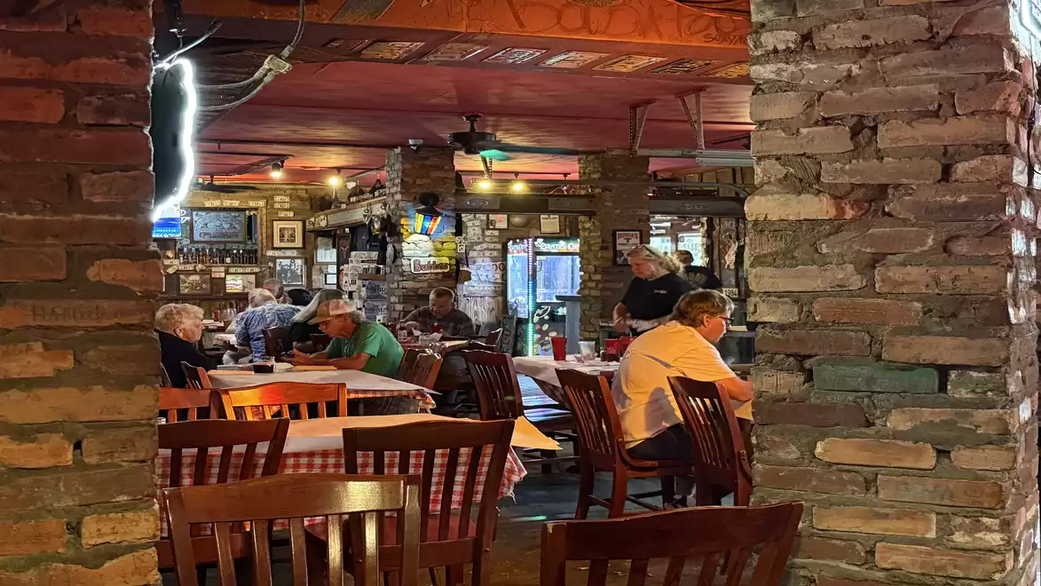 Cozy restaurant with brick walls and wooden tables where people are dining.