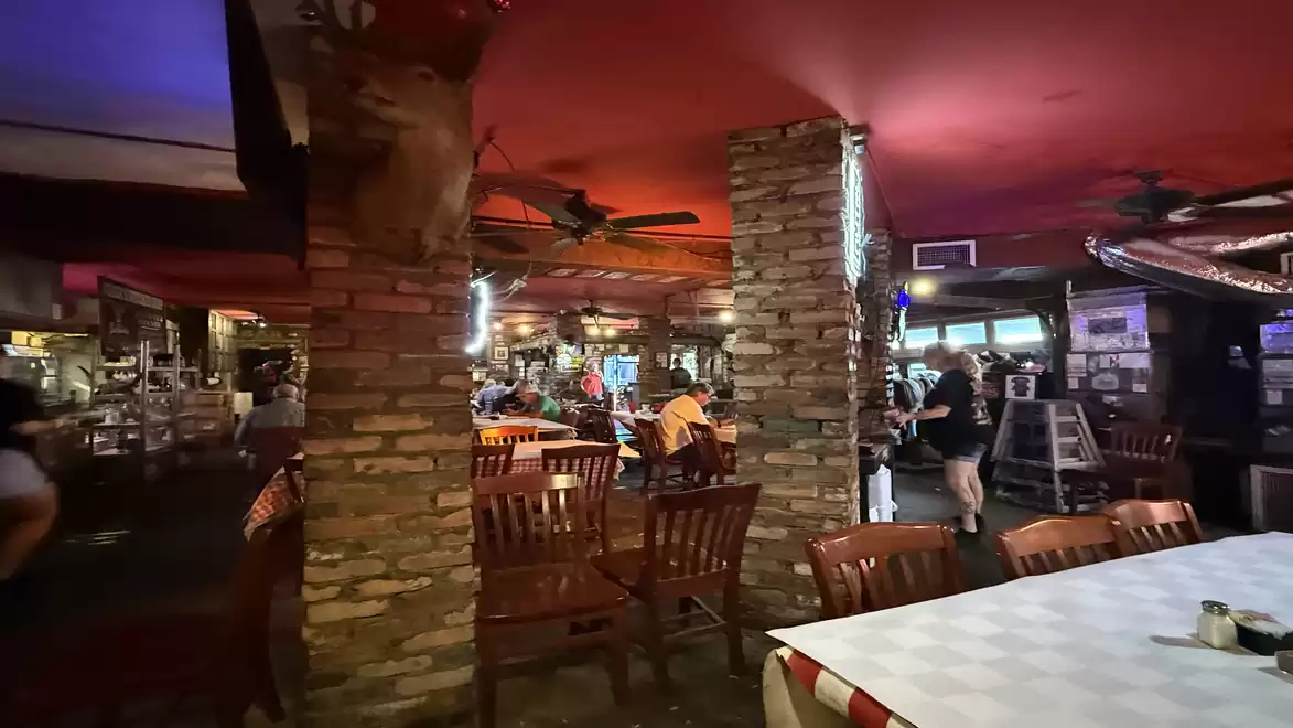 Cozy restaurant with rustic brick architecture and wooden chairs, illuminated by warm lighting.