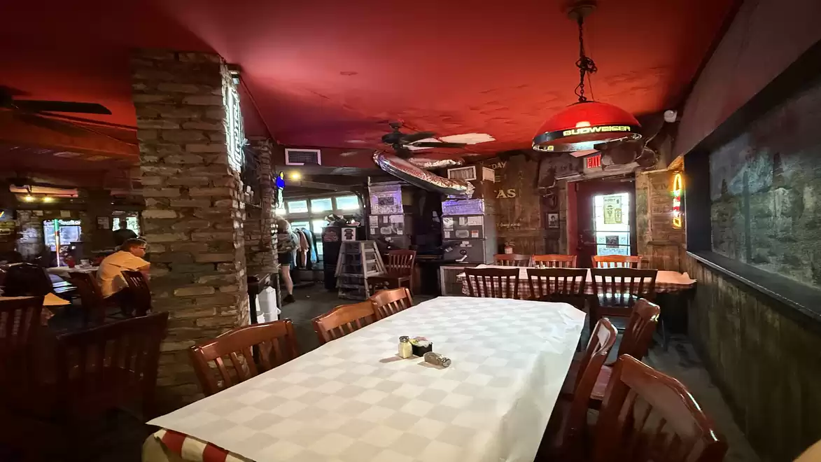 A cozy restaurant with brick walls and wooden ceilings, furnished with wooden furniture and decorative lights.
