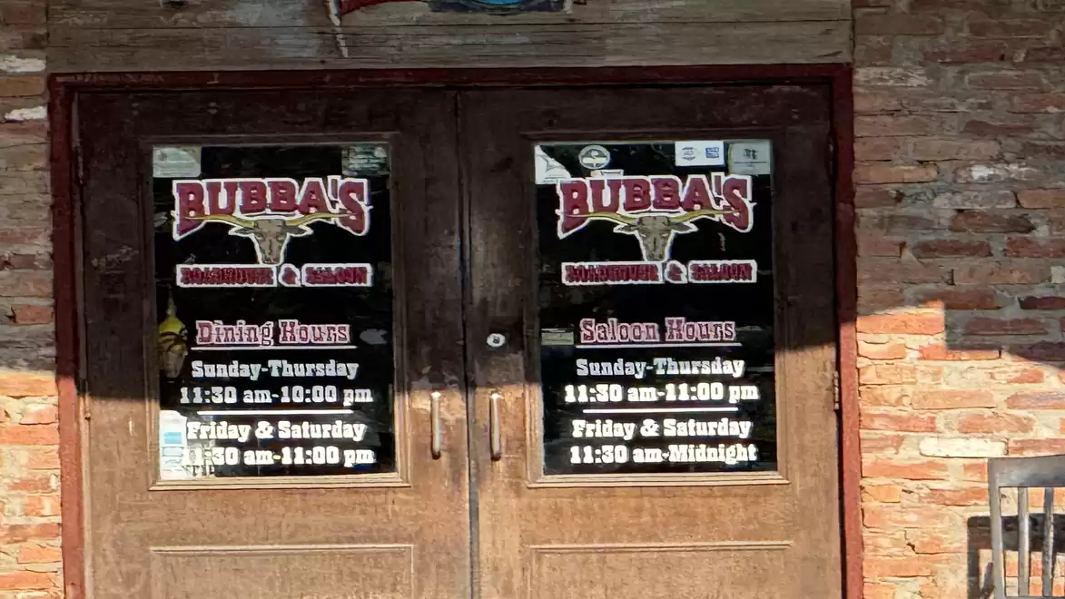 Wooden entrance doors of a restaurant with signage and opening hours.