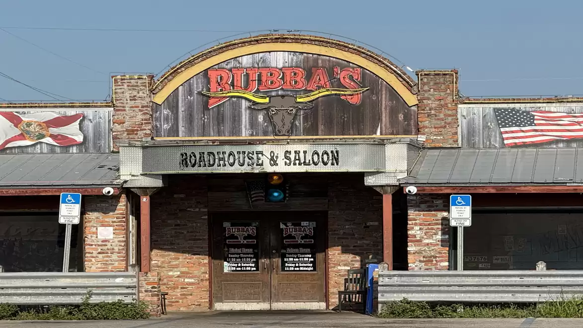 Exterior view of a rustic roadhouse and saloon with American flag and wooden facade.