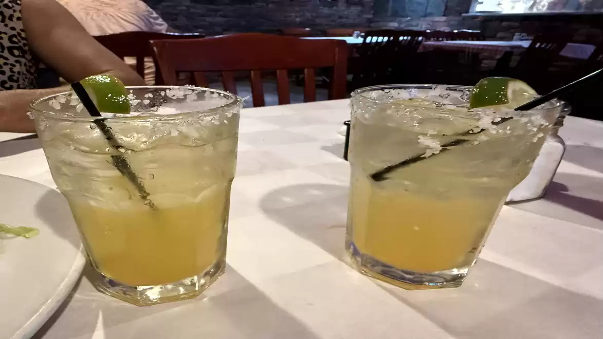 Two margarita glasses with lime slices on a restaurant table.