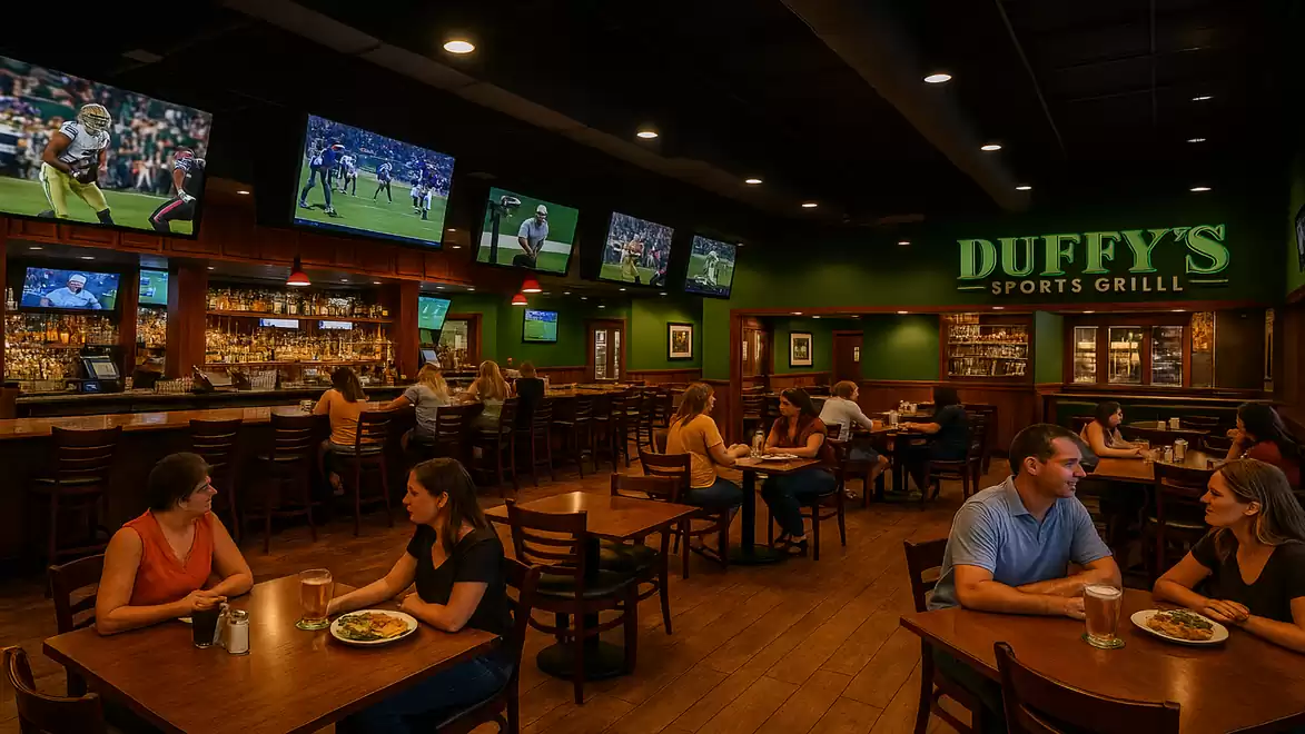 A busy sports restaurant with multiple TVs showing sporting events and guests eating and drinking at tables.
