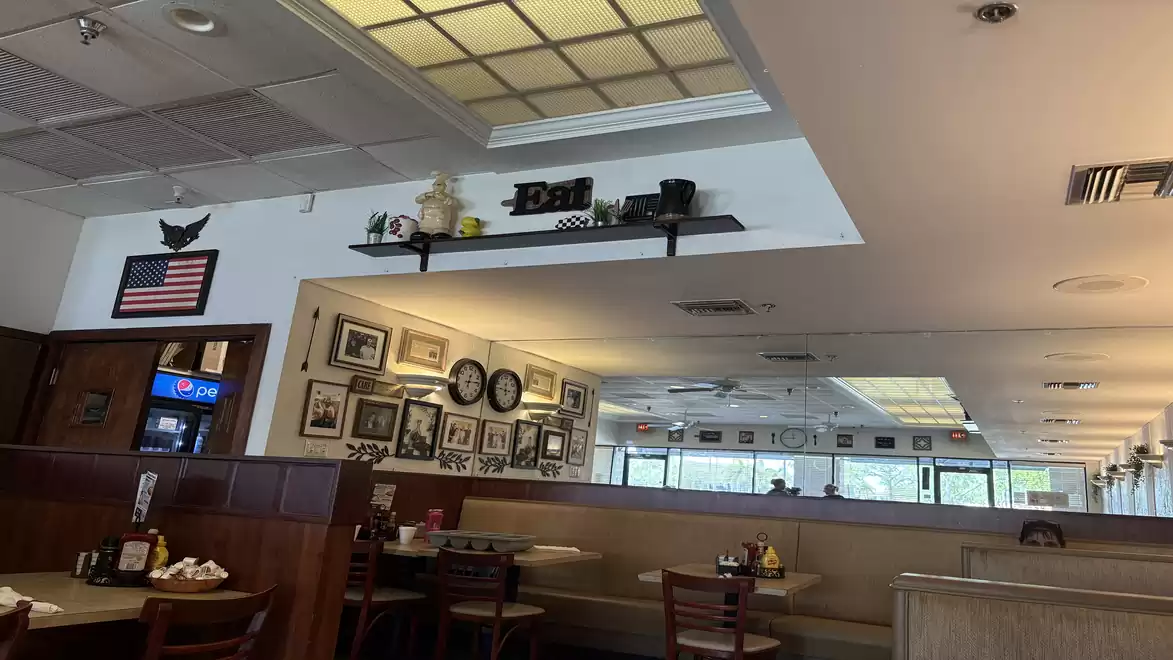 Interior view of a cozy restaurant with American decor, a flag on the wall, and a beverage dispenser.