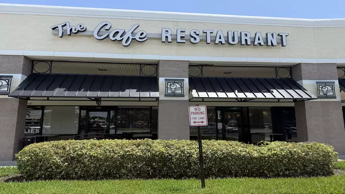 Exterior view of a cafe and restaurant with large windows and a sign reading 'The Cafe Restaurant'.