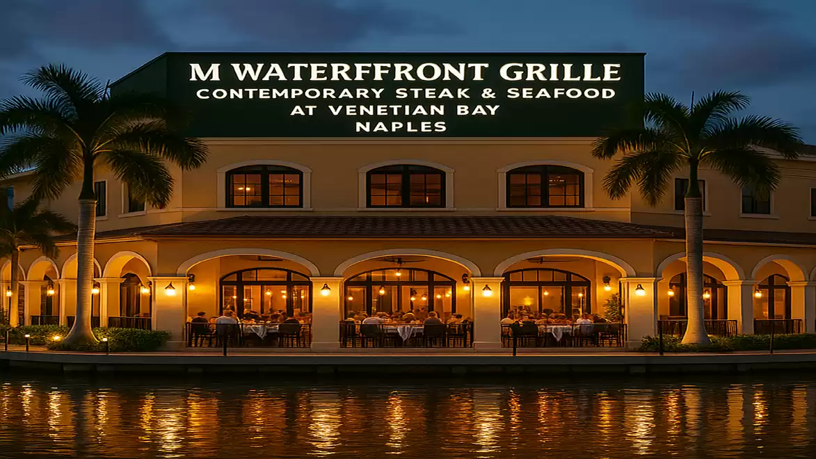 Illuminated waterfront restaurant with palm trees at dusk, M Waterfront Grille in Naples.