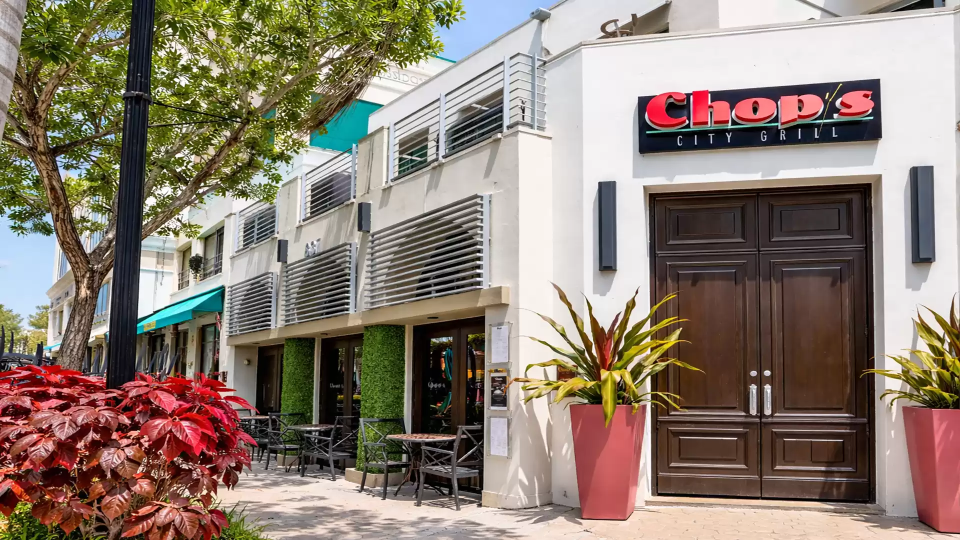 Exterior view of a modern restaurant with outdoor seating and green decor.