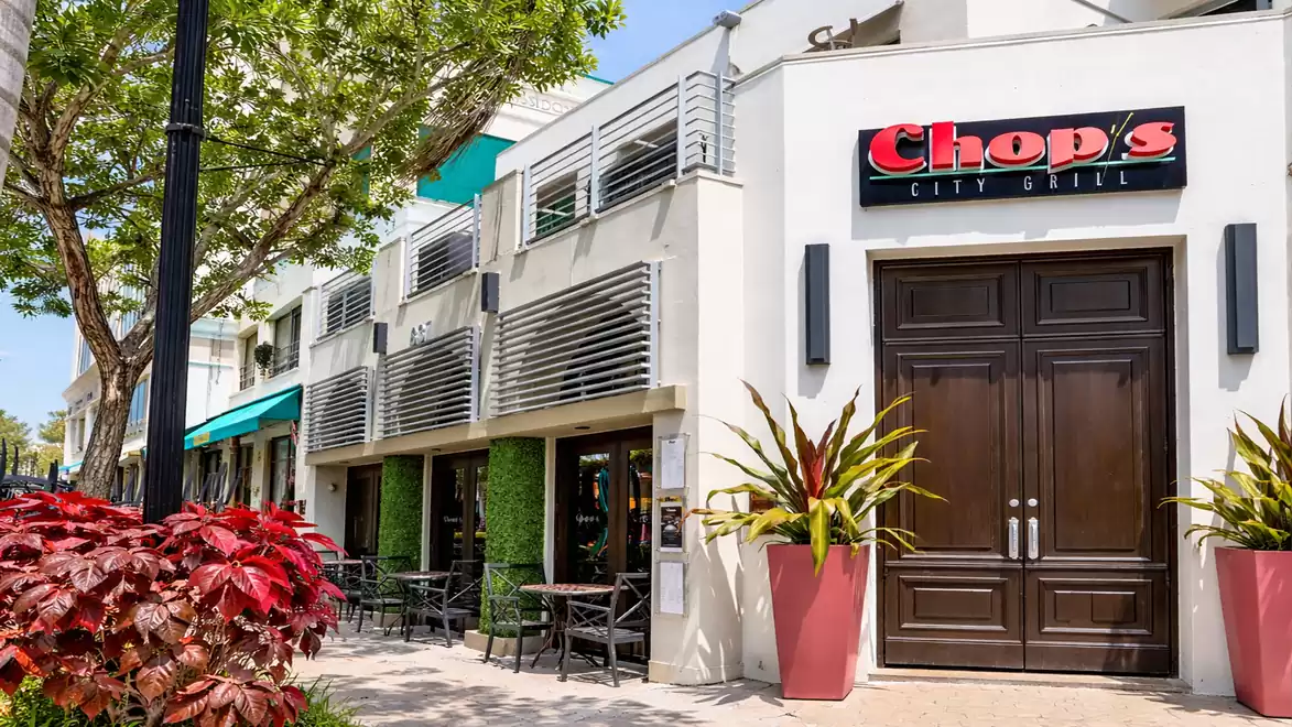 Exterior view of a modern restaurant with outdoor seating and green decor.
