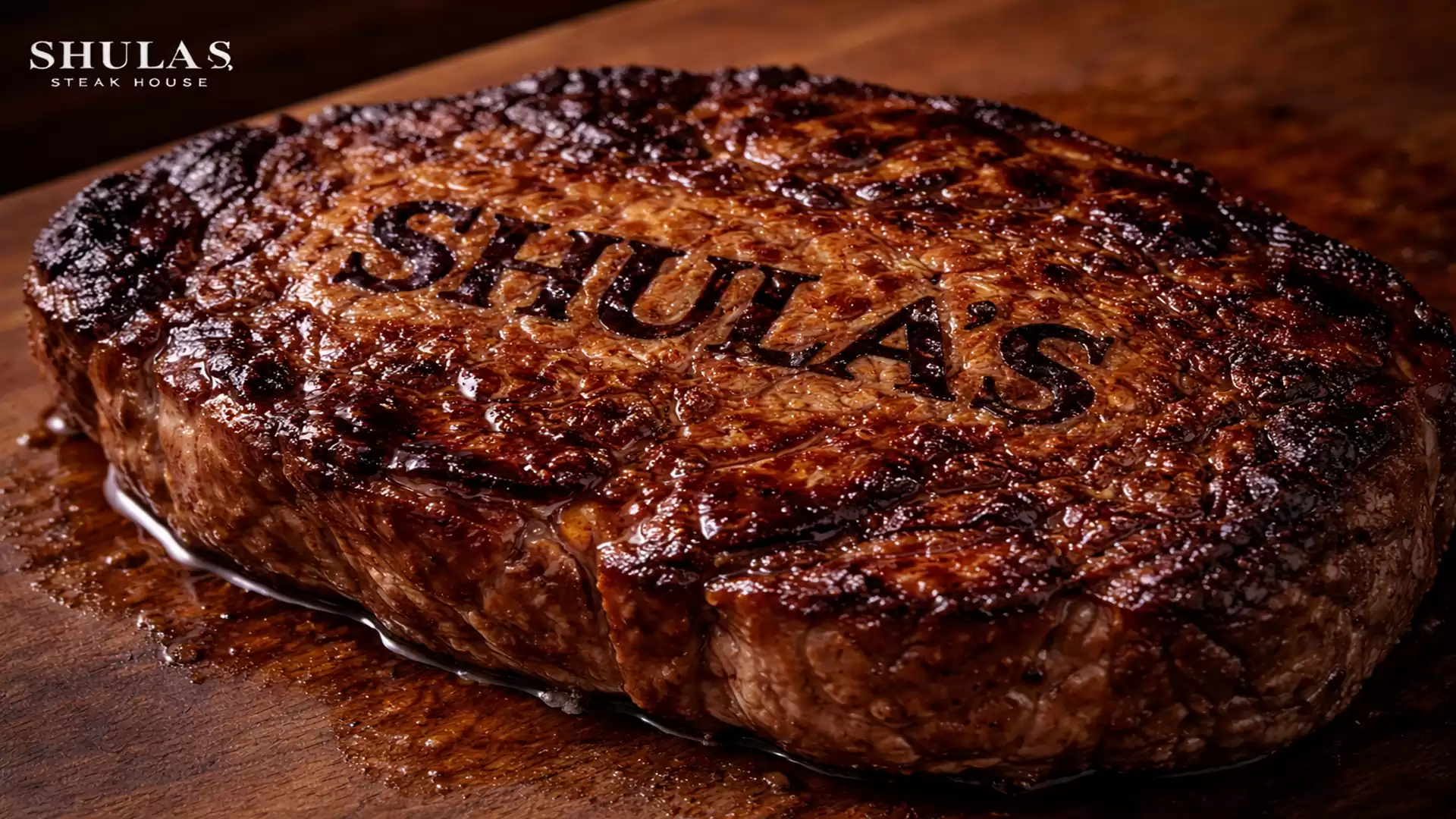 Close-up of a perfectly grilled steak with the engraved logo of Shula's Steak House on a wooden board.