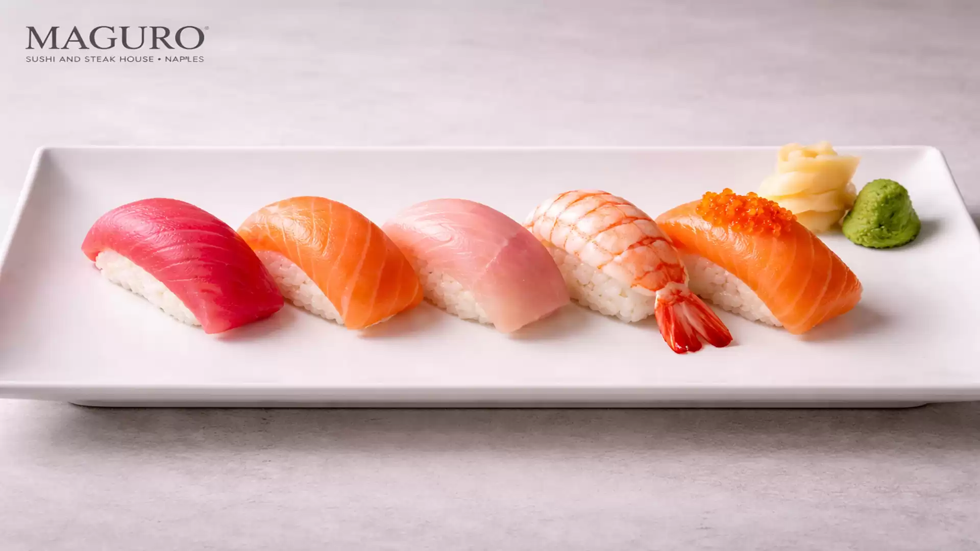 An elegant plate featuring a selection of nigiri sushi, including maguro tuna, salmon, and shrimp, served with wasabi and pickled ginger.
