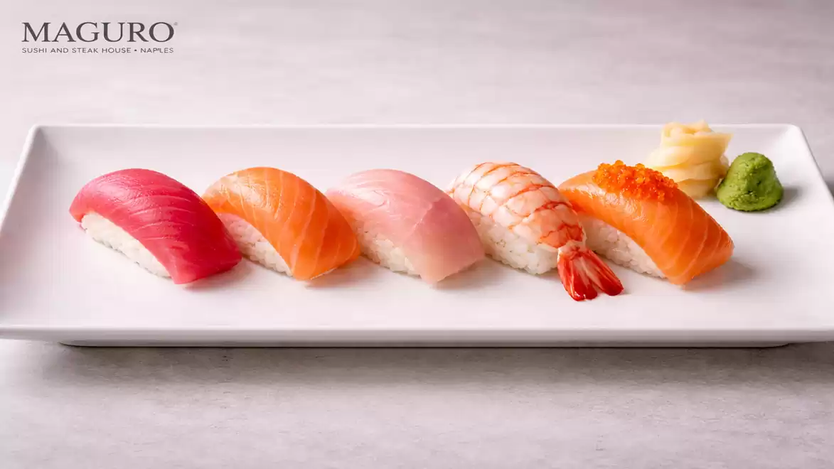An elegant plate featuring a selection of nigiri sushi, including maguro tuna, salmon, and shrimp, served with wasabi and pickled ginger.