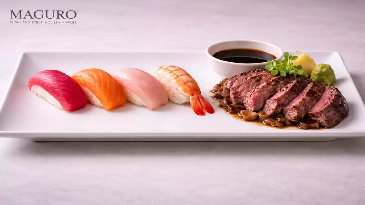 Elegant sushi arrangement with nigiri and beef slices on a white plate, accompanied by soy sauce, ginger, and wasabi.