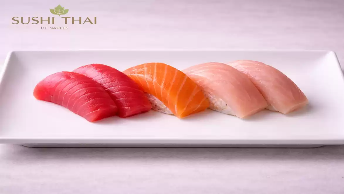 An elegant white rectangular plate with four delicious sushi nigiri pieces, featuring tuna, salmon, and other fish varieties.
