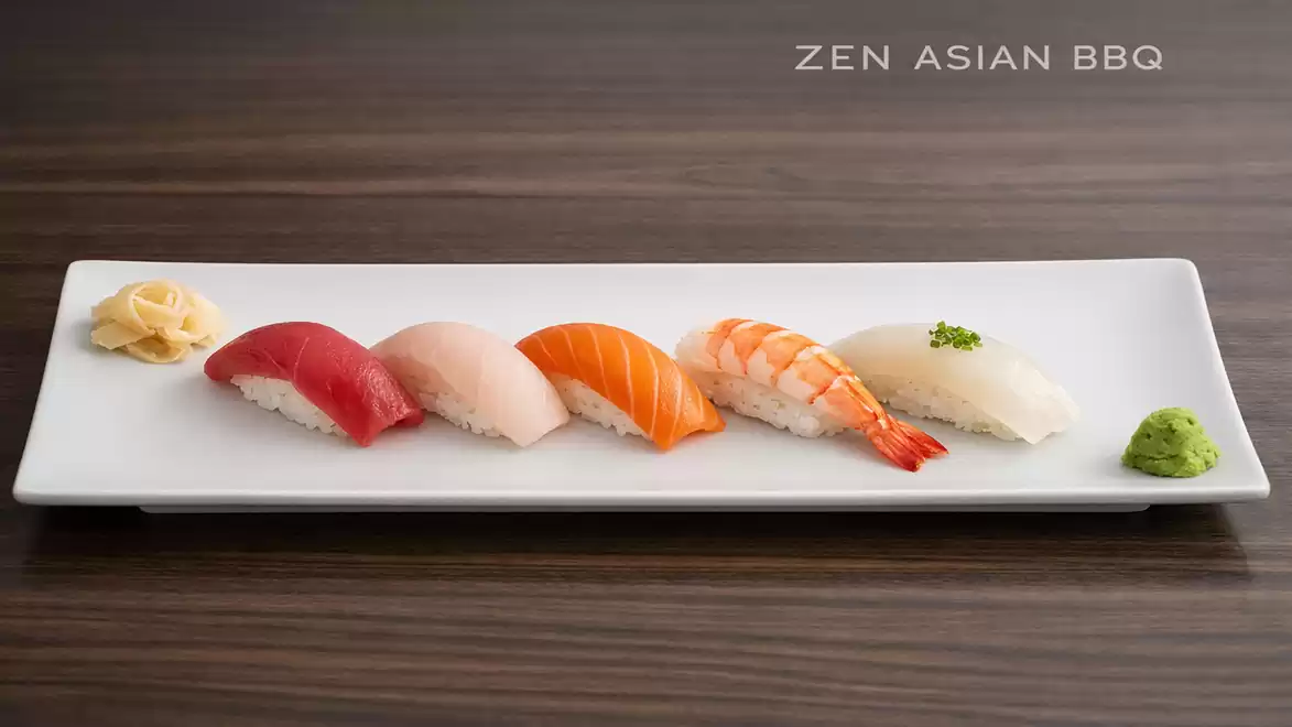 An elegant sushi platter featuring five different types of nigiri and wasabi on a white plate. Perfect for Japanese cuisine lovers.