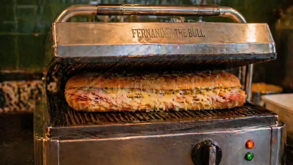 A sandwich being grilled in a Panini press called 'Fernando the Bull'.