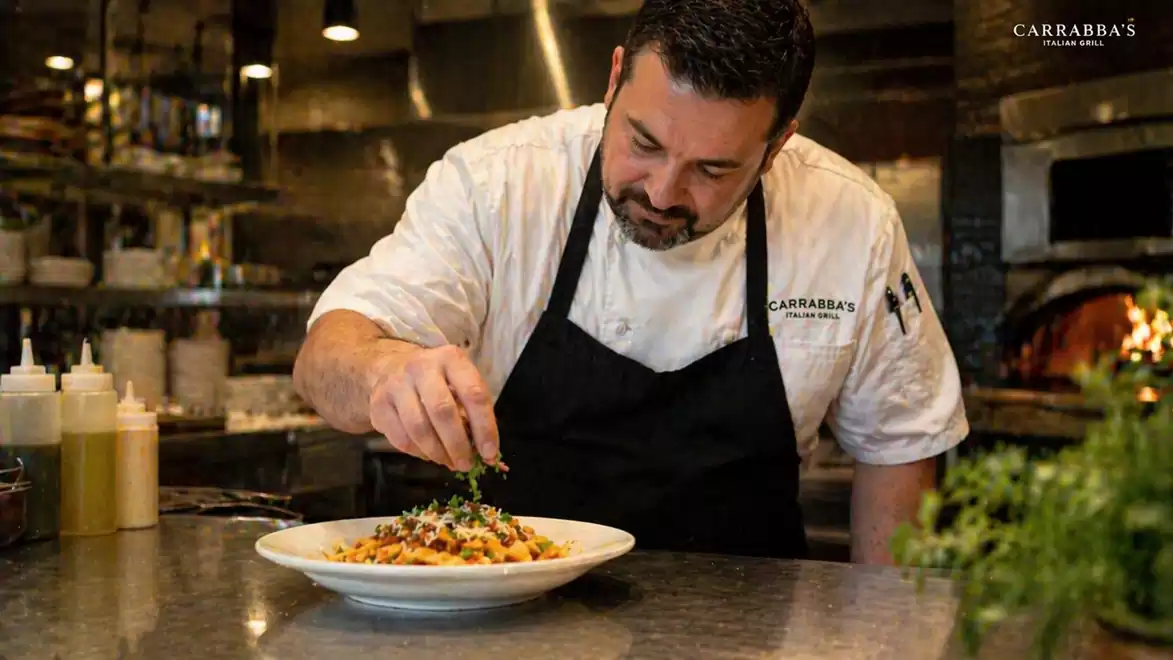 A chef garnishes a dish in a professional kitchen.