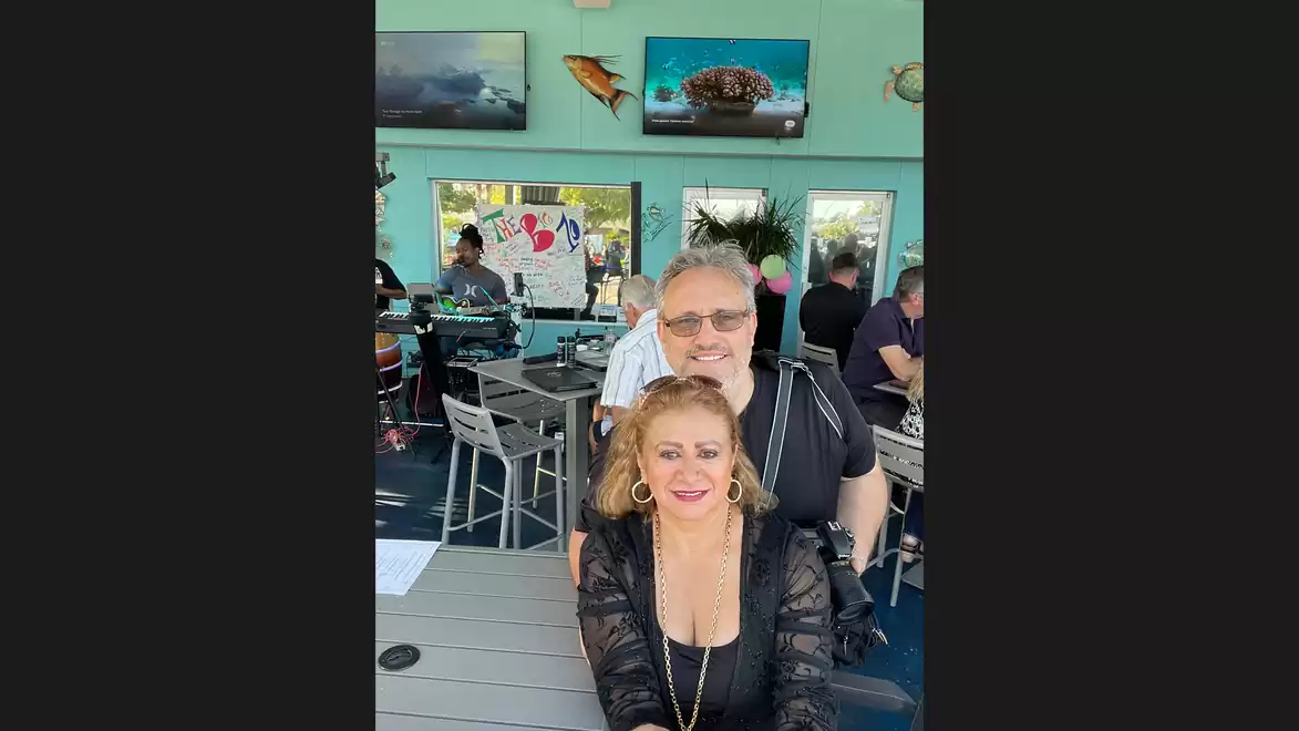 Couple in a restaurant with light blue walls, artwork in the background and a busy atmosphere.