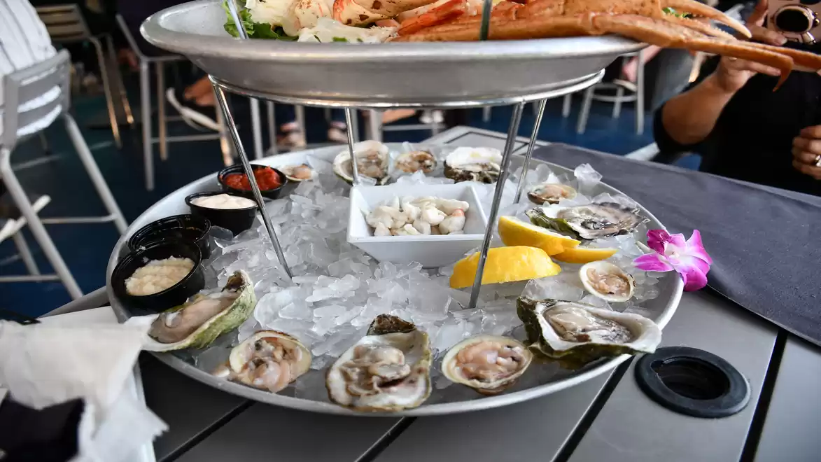 An elegant seafood platter featuring fresh oysters, lemon slices, and other seafood served on a bed of ice.
