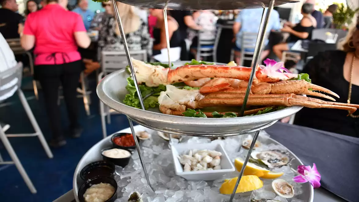 A rich platter of seafood, shrimp, and lemon served on ice in a busy restaurant.