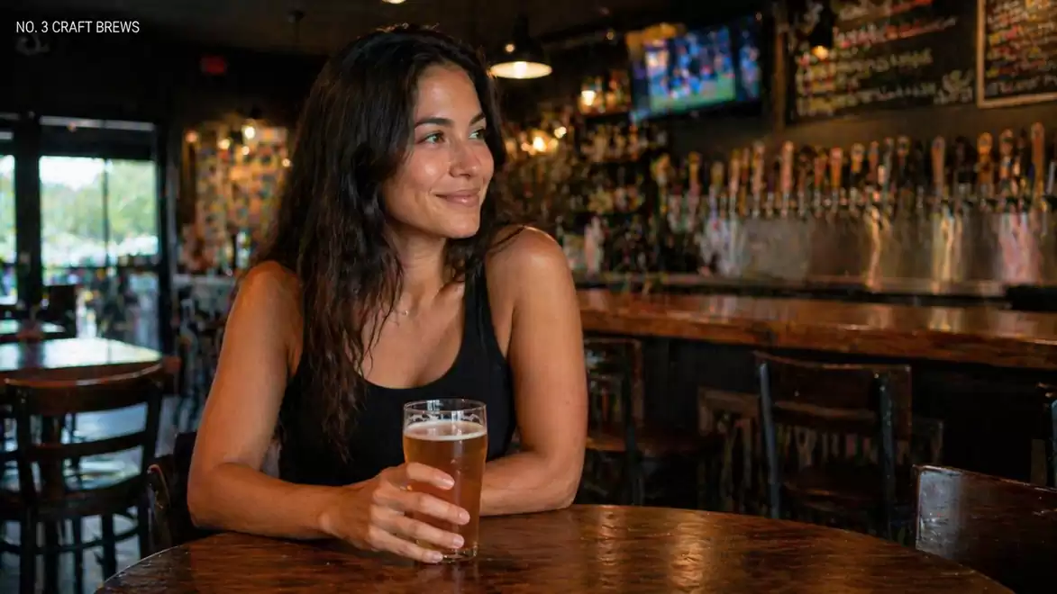 A woman sits in a bar, enjoying a glass of beer and smiling. In the background, there are many beer taps and a cozy atmosphere.