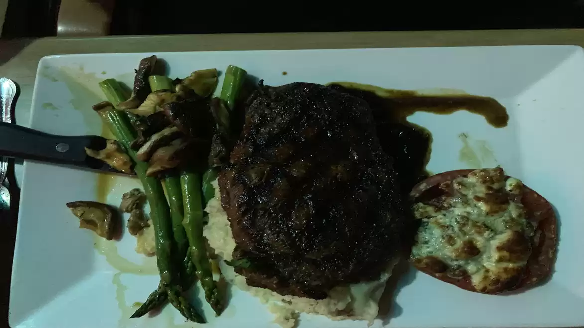 A plate featuring a juicy steak on puree, served with asparagus and baked tomato.