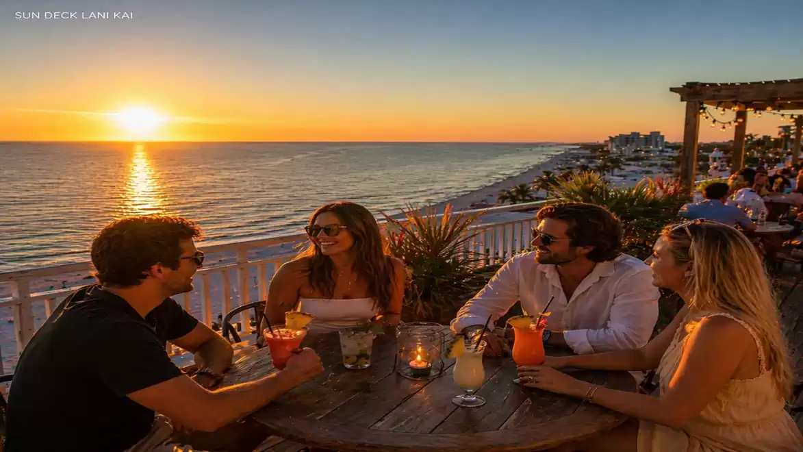 Four people sitting at a table enjoying drinks with a sea view at sunset.