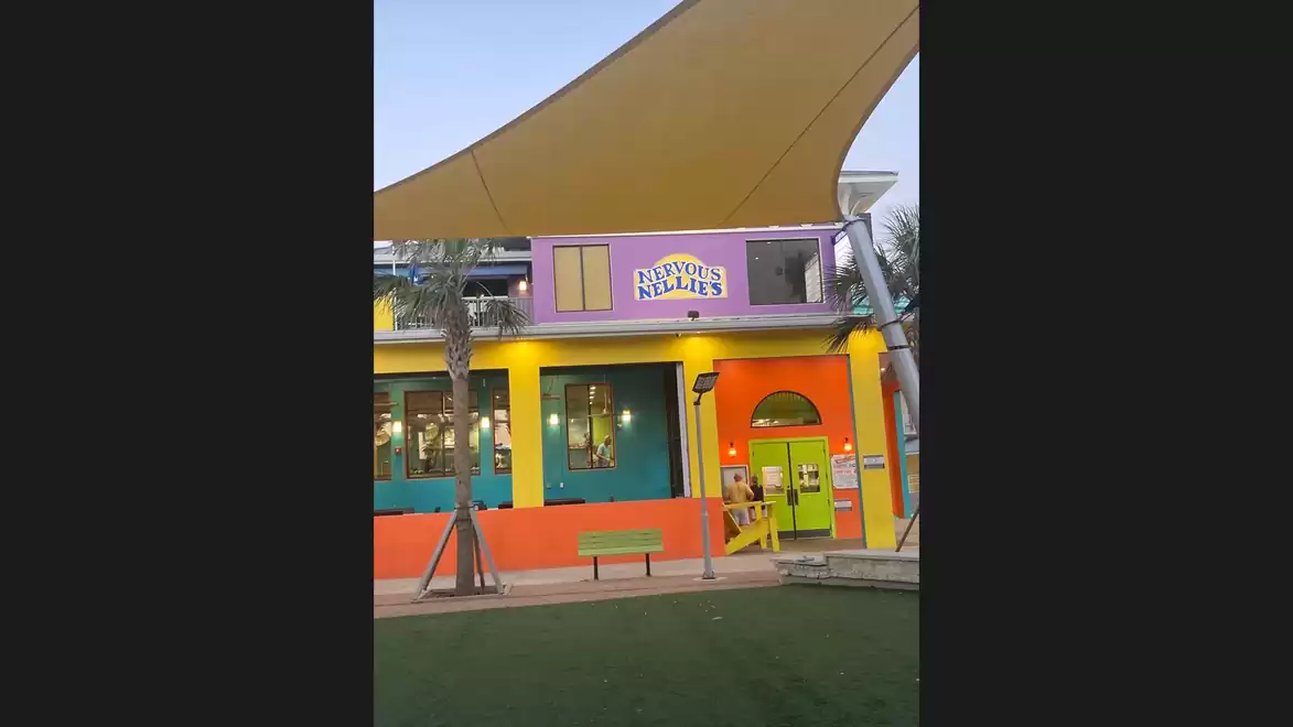 Colorful building with yellow canopy and palm trees in the foreground.