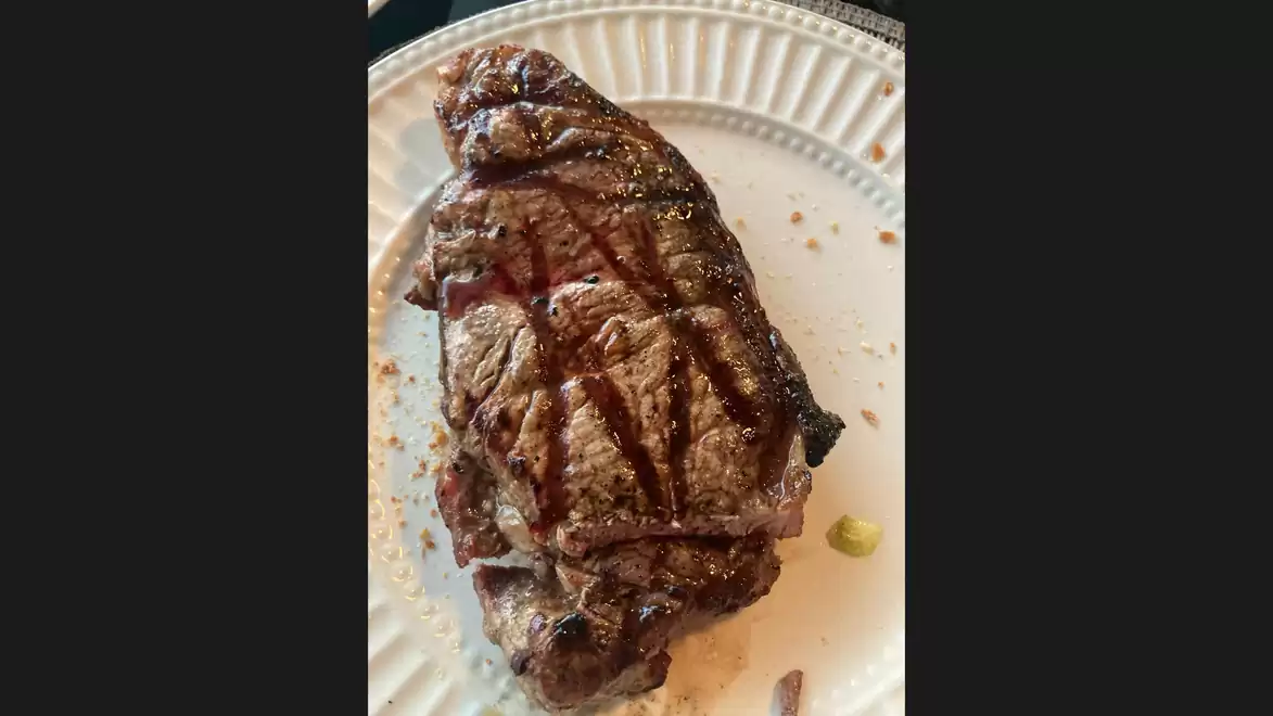 Juicy, perfectly grilled steak on a white plate. Grill marks visible.
