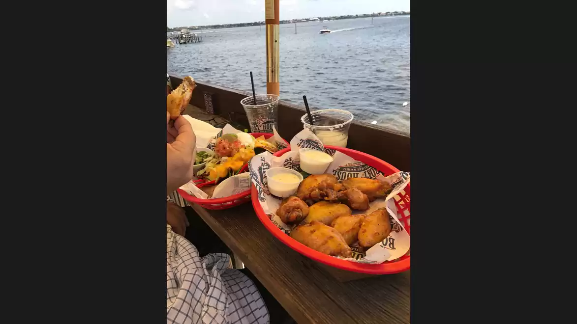 A table with various dishes in red baskets on a terrace overlooking a body of water.