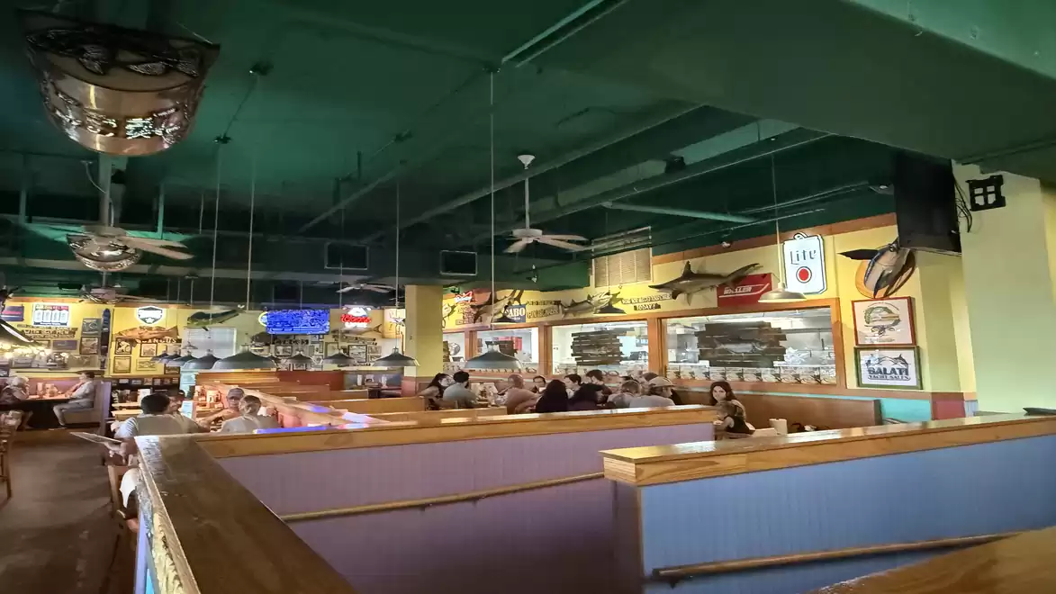 Interior of a cozy restaurant with blue booths, wooden decorations, and decorative fish on the walls.